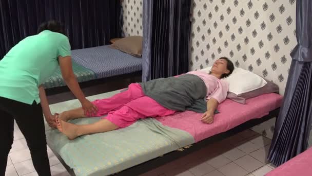 Thai massage. A woman is lying on the bed. The masseuse kneads the womans shin. — Stock Video