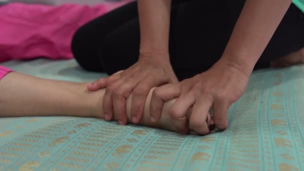 Masaje tailandés. Una mujer está acostada en la cama. La masajista masajea el pie femenino . — Vídeos de Stock