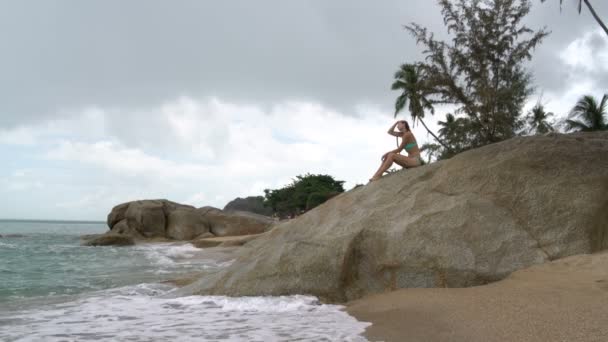 Donna sulla spiaggia seduta su una roccia in riva al mare — Video Stock