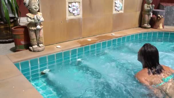 De vrouw zwemt naar de jacuzzi en gaat zitten in het. — Stockvideo