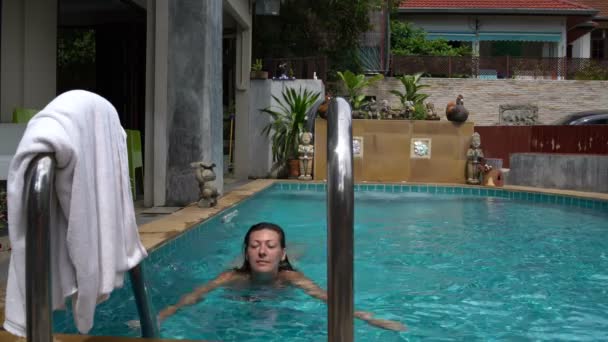 Uma mulher sai da piscina e toma uma toalha — Vídeo de Stock