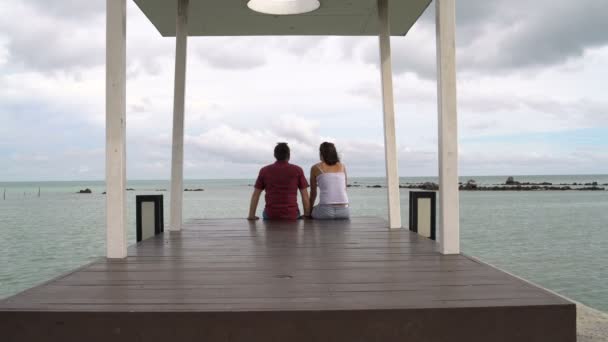 Bir erkek ve bir kadın iskele deniz kenarında oturmak — Stok video