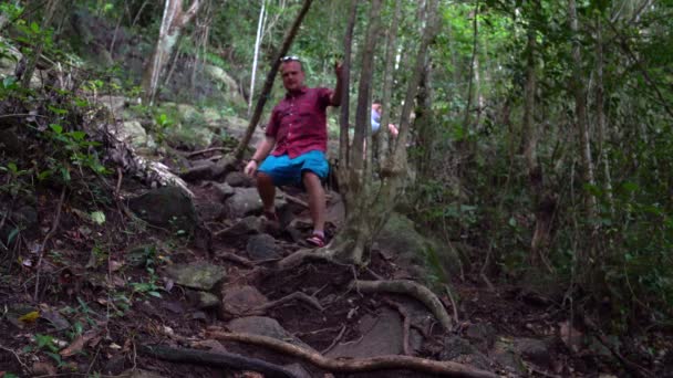 나무의 뿌리를 따라 가파른 산에서 한 남자가 내려 — 비디오