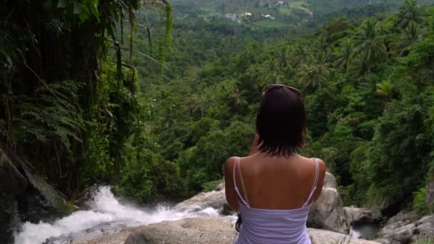 Una mujer se sienta junto a la cascada — Vídeo de stock