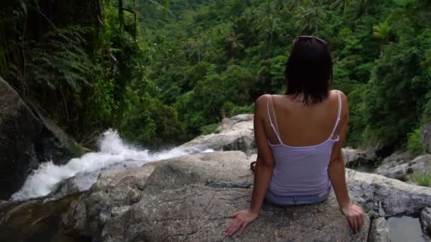 Žena sedí na vrcholu vodopádu — Stock video