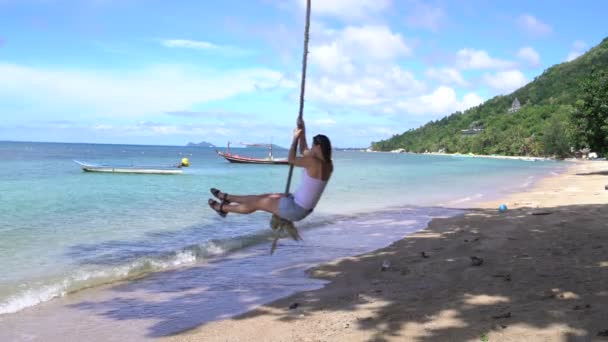 Mujer balanceándose en una cuerda en la playa en la orilla del mar — Vídeo de stock
