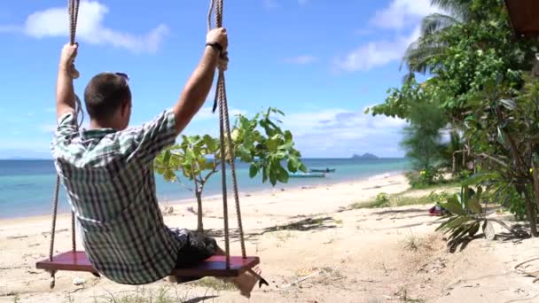 Ein Mann schwingt auf einer Schaukel am Meer — Stockvideo