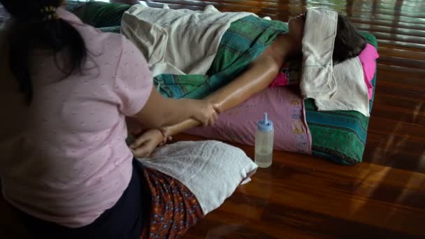 Масажистка ставить нафти з боку жінки і робить масаж — стокове відео