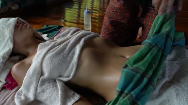Thai body massage. The masseuse covers a woman with a rug and does a massage — Stock Video