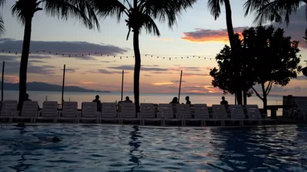 Un hombre está nadando en la piscina al atardecer — Vídeo de stock