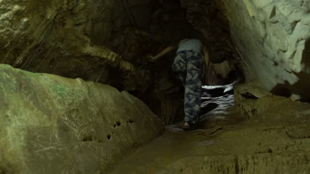 Una mujer camina por un túnel en una cueva — Vídeos de Stock