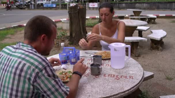 Comida callejera tailandesa. Hombre y mujer comiendo fideos con verduras — Vídeos de Stock