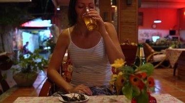 Bir kadın bira içiyor ve bir Tayland restoranı kavrulmuş bir çekirge yiyor