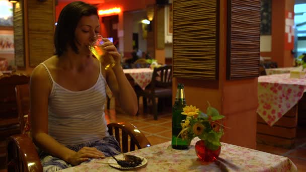 En kvinna äta en rostad gräshoppa och dricka öl i en thailändsk restaurang — Stockvideo