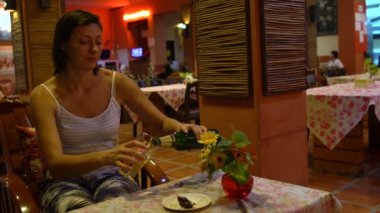 Bir Tayland restoranı, bir masada oturan bir kadın bira bir cam içine dökülen.