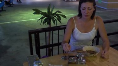 Bir kadın baharat gıda koyarak ve keçe Tay çubukla yemek Tayland bir kafede oturuyor