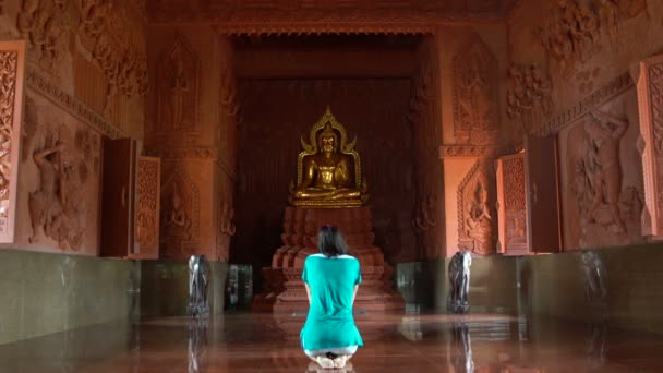 Kvinnan ber innan en staty av Buddha i buddhistiska tempel — Stockvideo