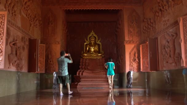 Un uomo sta fotografando una donna su uno smartphone vicino a una statua di Buddha in un tempio buddista — Video Stock