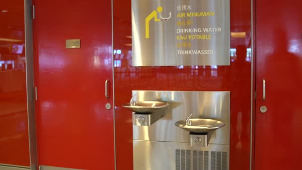 Kvinna dricka buteljerat vatten från en fontän på flygplatsen — Stockvideo