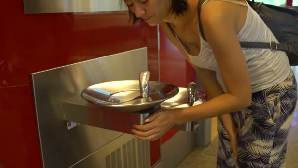 Uma mulher bebendo água de uma fonte no aeroporto — Vídeo de Stock