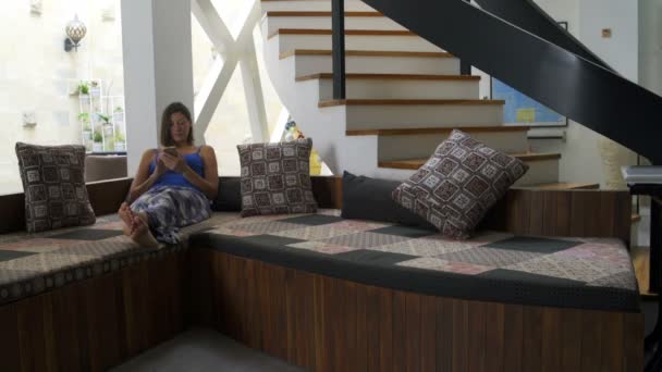 Bir kadın evde bir smartphone ile kanepede yatıyor — Stok video