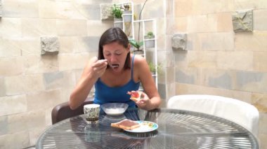 Bir kadın reçel ile müsli ve kızarmış ekmek yiyor