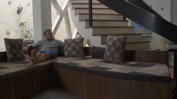 Člověk si klade na gauči doma — Stock video