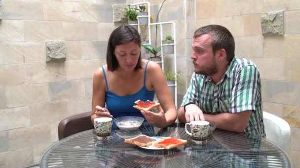 A man and a woman sitting at a table eating muesli and toast with jam — Stock Video