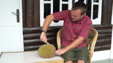 Bir adam bir durian bıçakla keser.