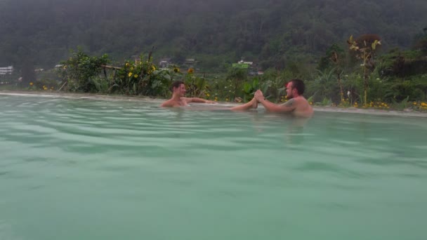 Un hombre está haciendo un masaje de pies de mujer en una piscina con agua caliente de sulfuro de hidrógeno — Vídeos de Stock