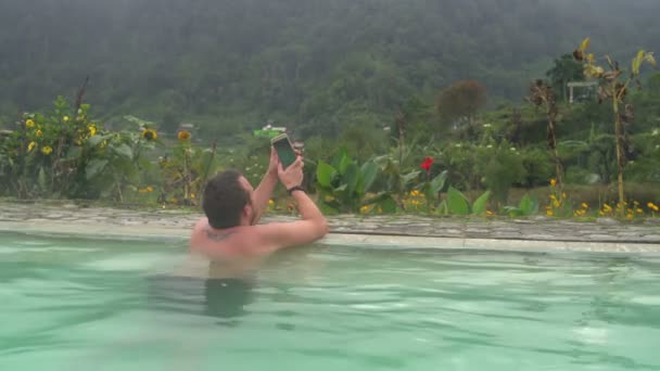 En man gör selfi i en pool med termalvatten — Stockvideo