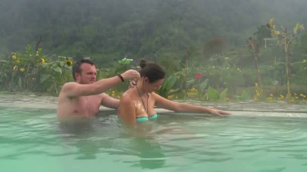 Een man massages een dames terug in een zwembad met thermaal water — Stockvideo