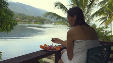 Bir kadın bir göl ve dağların fon karşı bir havlu oturuyor ve çilek yiyor