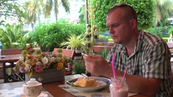Ein Mann sitzt in einem Restaurant und telefoniert — Stockvideo