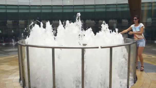 Une femme marche autour d'une fontaine — Video