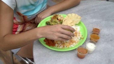 Sokak Hint yemeği Thali. Kadın soslu pirinç dökülen ve elleriyle yiyor