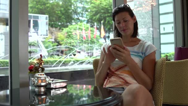 Μια γυναίκα κάθεται στο λόμπι του ξενοδοχείου με θέα το σιντριβάνι — Αρχείο Βίντεο