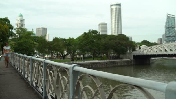 Nő sétál át a hídon a folyó felett — Stock videók