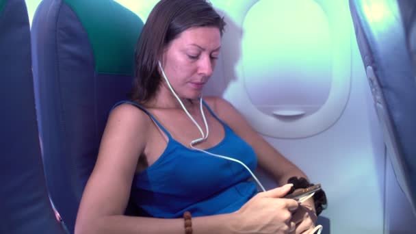 La mujer en el avión escuchando música con auriculares — Vídeos de Stock