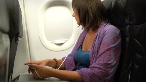 Μια γυναίκα σε ένα αεροπλάνο εγείρει μια κουρτίνα φινιστρίνι, κοιτάζει έξω από το παράθυρο και μειώνει την curtainporthole — Αρχείο Βίντεο