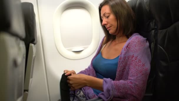 Uma mulher em um avião veste uma máscara em seus olhos — Vídeo de Stock
