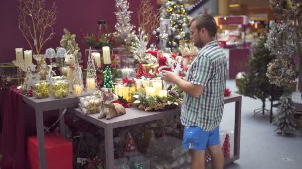 Un hombre elige juguetes de Navidad en el centro comercial — Vídeo de stock