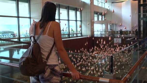 Женщина смотрит на кинетический дождь в аэропорту Сингапура — стоковое видео
