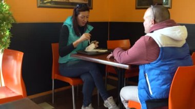 Bir kadın ve bir adam bir kafede masada oturan ve konuşuyor. Ekmek çorbası yemek kadın. Bir adam ayağa kalkar ve yaprakları