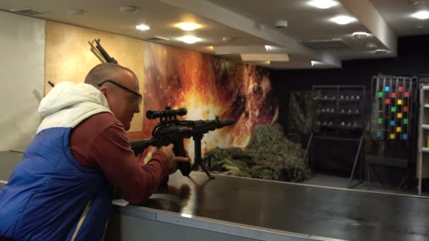Um homem de óculos aponta e dispara uma metralhadora contra alvos metálicos . — Vídeo de Stock