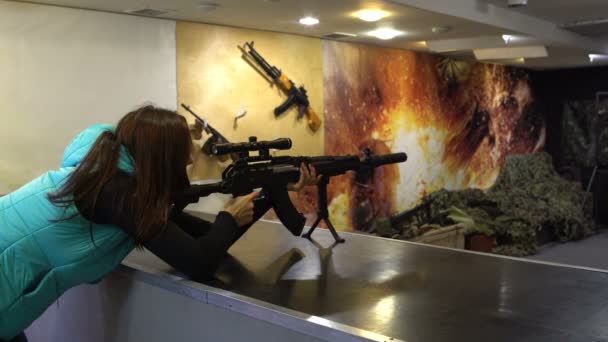 Shooting range. A woman in glasses aims and shoots from a Kalashnikov assault rifle. — Stock Video