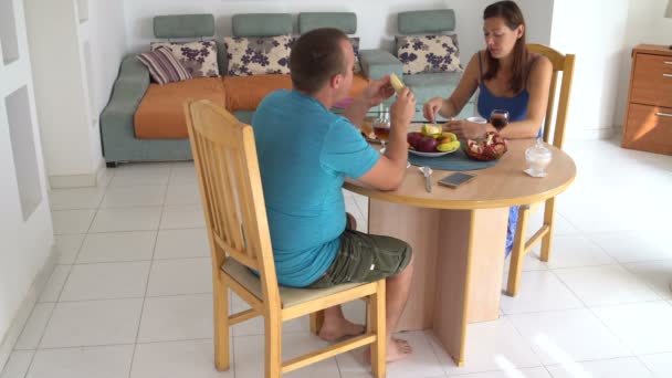 Mulher e homem estão sentados na mesa em casa almoçando e conversando — Vídeo de Stock