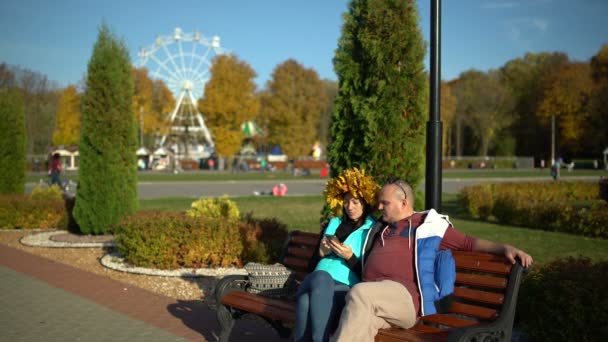 Paar zittend op een bank in een park met een Smartphone — Stockvideo