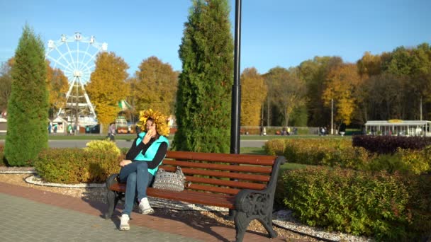 Frau isst Eis im Park auf einer Bank — Stockvideo