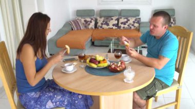 Aile öğle yemeği masada evde olması. Kadın ve adam tereyağı ve bal ekmek üzerinde yayılmış